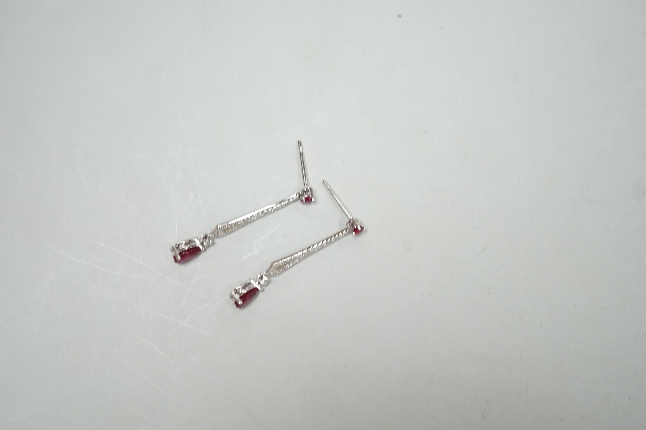 A modern pair of 18k white metal, ruby and diamond cluster set line drop earrings, 30mm, gross weight 2.2 grams.